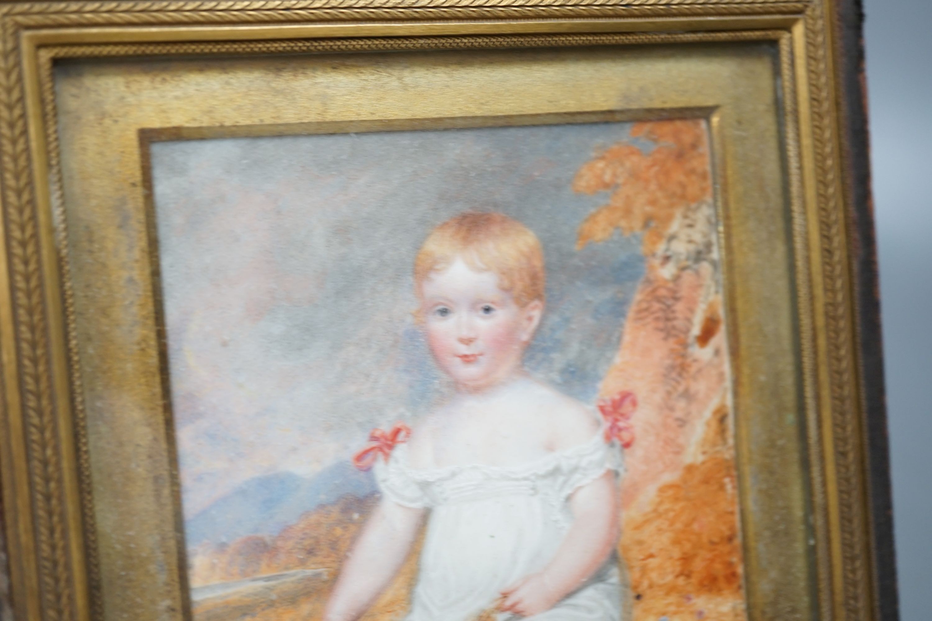 A 19th century portrait miniature on ivory of an infant, with racket and ball, 10 cms wide x 14 cms high.